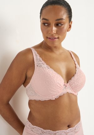 Roze bh met kantafwerking en bloemenpatroon, zachte cups, verstelbare bandjes en een strikdetail in het midden; bijpassende kanten slip zichtbaar eronder.