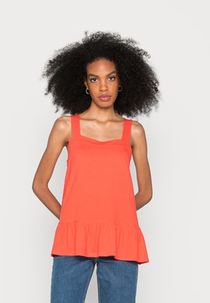 Top sem mangas coral com decote quadrado, alças largas e bainha com volantes. O material parece suave e leve. Combinado com jeans azuis.
