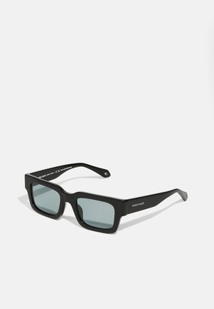 Óculos de sol retangulares pretos com uma armação grossa e lentes cinza polarizadas. Apresentam um acabamento mate suave e um discreto detalhe do logotipo nas hastes.