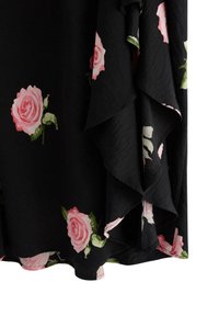 Tessuto nero con orlo ondulato, decorato con grandi rose rosa e foglie verdi. Il materiale ha un aspetto leggermente testurizzato.