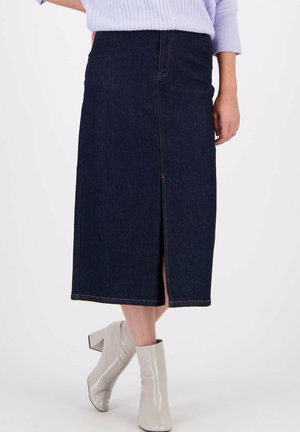 Donkerdenim midi-rok met een voorknip, voorzien van oranje stiksels en een aansluitende silhouette. Gecombineerd met lichtgrijze enkellaarsjes.