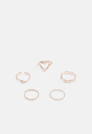 Set van vijf roségouden ringen met verschillende ontwerpen: een hartvorm, een gedraaide band, een golvende rand en getextureerde accenten.
