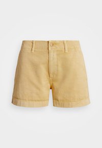 Žluté lněné kraťasy klasického střihu, s předním zapínáním na knoflík, poutky na opasek a ohrnutými lemy. Hladká textura a minimální detaily.