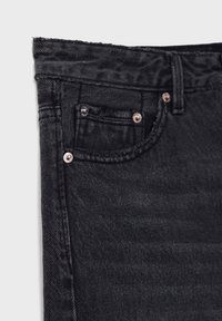 Primer plano del área del bolsillo frontal de unos jeans de mezclilla negra con el lazo del cinturón y remaches metálicos en la costura y las esquinas del bolsillo.