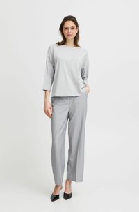 Lichtgrijs oversized t-shirt met driekwartmouwen, gecombineerd met lichtgrijze, wijde broek en zwarte, puntige flats.