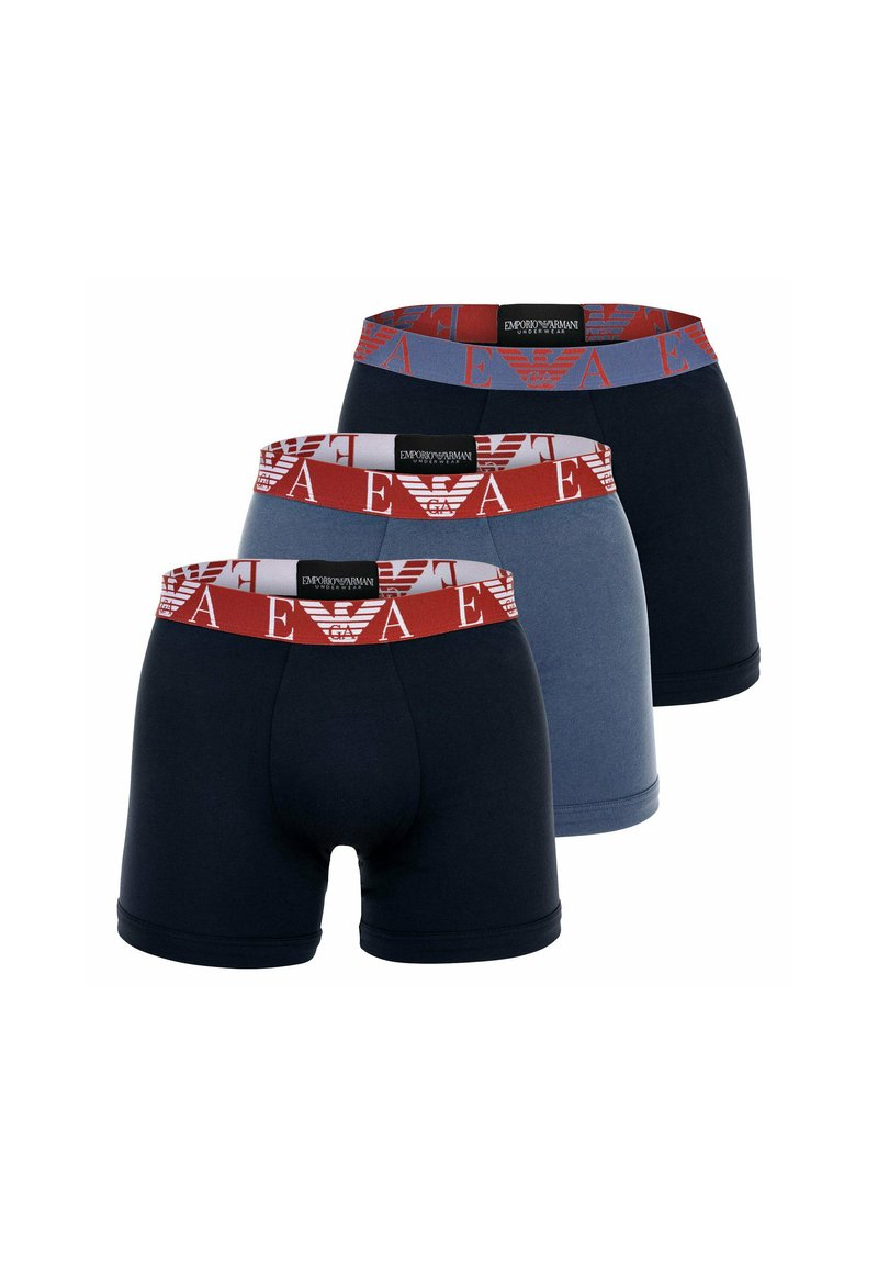 Drie paar herenslipjes in marineblauw, lichtblauw en donkerblauw, voorzien van elastische tailles met een rode logo patroon.