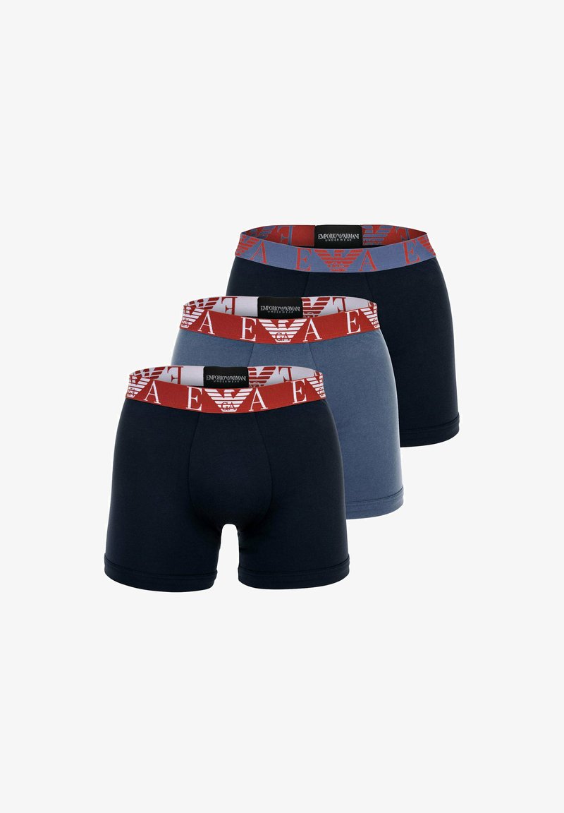 Drie paar herenslipjes in marineblauw, lichtblauw en donkerblauw, voorzien van elastische tailles met een rode logo patroon.