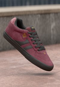 Maroon suede sneaker with gray accents, black outsole, and flat gray laces. Features logo detailing and a padded collar for comfort.