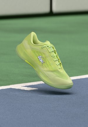 Leuchtend grüner Sportschuh mit einem Obermaterial aus Mesh, flachen Schnürsenkeln und einem weißen Logo. Leichtes Design mit einer strukturierten Außensohle, die für Sport geeignet ist.