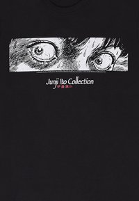 Zwart katoenen t-shirt met een witte afbeelding van twee ogen met gedetailleerde lijnen en schaduwen. De tekst eronder luidt "Junji Ito Collection" in het rood.