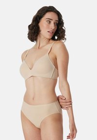 Reggiseno nudo con coppe triangolari e spalline regolabili, abbinato a slip alti nudi. Tessuto liscio con cuciture minimali.