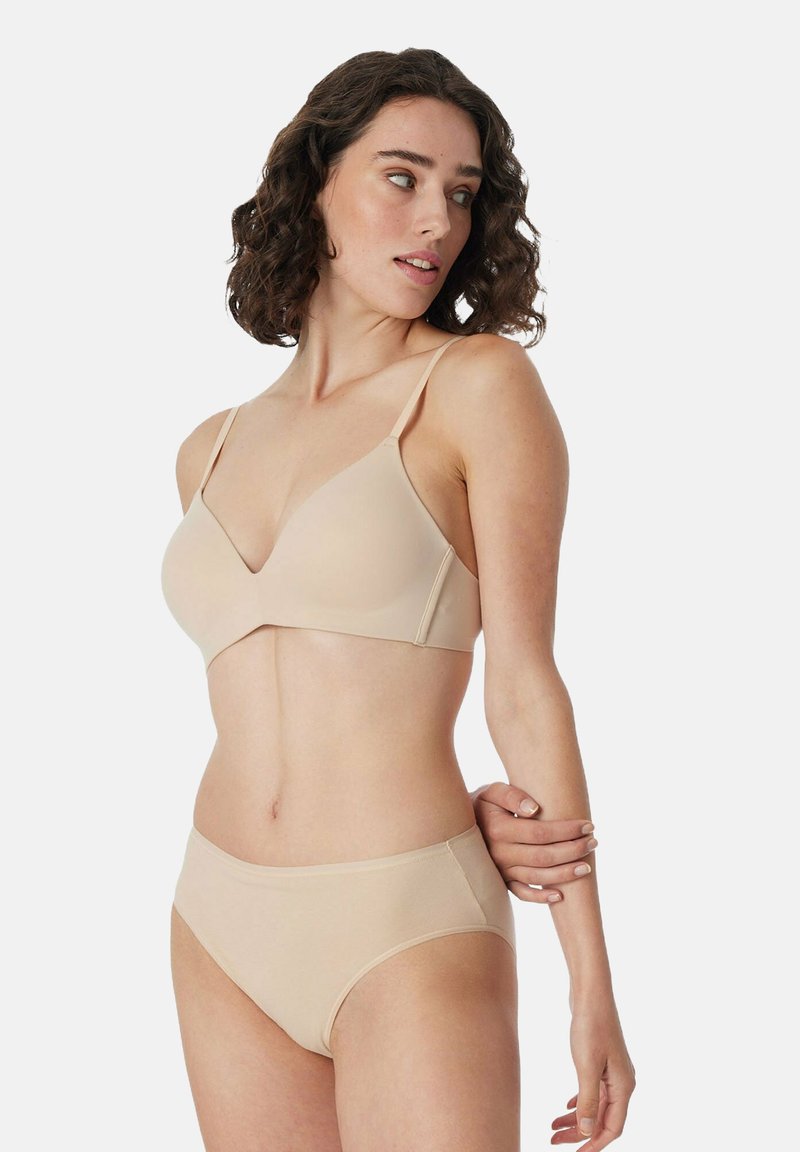 Reggiseno nudo con coppe triangolari e spalline regolabili, abbinato a slip alti nudi. Tessuto liscio con cuciture minimali.