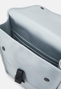 Svetlomodrá taška vyrobená z hladkého materiálu, so čiernym kovovým uzáverom a vnútornou vreckom so sivým podšívkou.