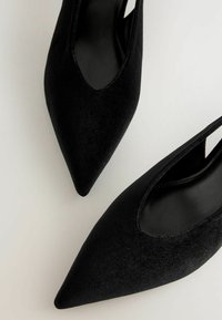 Svarta satinspetsiga skor med utskärningsdesign och en slät, matt yta, med en elegant silhuett och öppen häl.