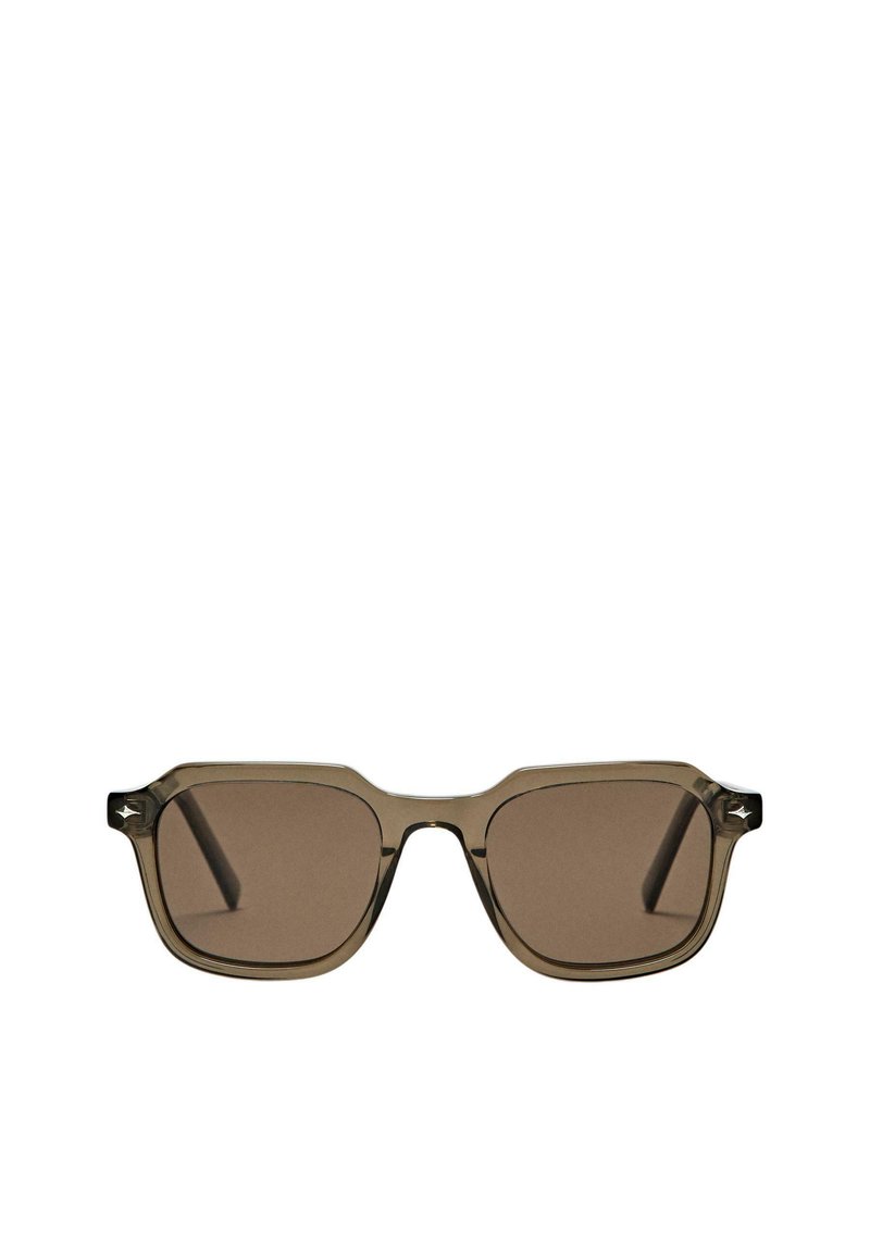 Brązowe okulary przeciwsłoneczne o kwadratowym kształcie, przezroczysta brązowa oprawka i subtelne srebrne akcenty na zausznikach.