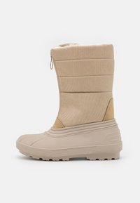 Botas impermeables beige con un upper de tela texturizada, cierre de cremallera y suelas de goma para tracción. Presentan un interior acolchado.