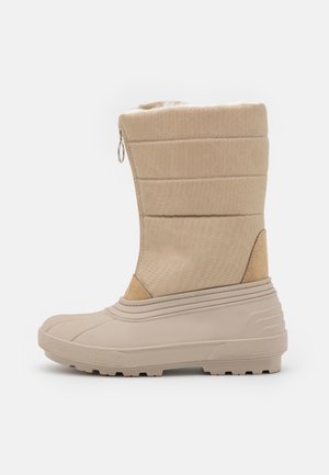 Bottes imperméables beiges avec une tige en tissu texturé, une fermeture éclair et des semelles en caoutchouc pour une meilleure traction. Elles disposent également d'un intérieur rembourré.