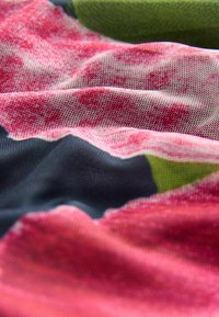 Mångfärgad tyg med en blandning av rosa, grön och marinblå nyanser, med en slät, texturerad yta och mjuka veck.