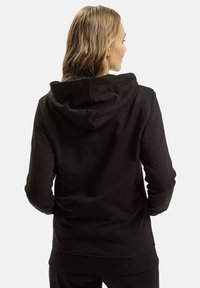 Czarna bluza z kapturem posiadająca podszewkę, długie rękawy i ściągacze. Materiał wydaje się miękki i swobodny, idealny na luźne noszenie.