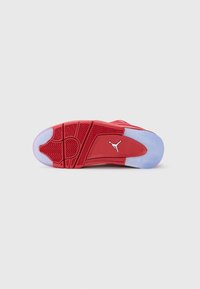 Rød sneakersål med et tekstureret herringbone-mønster, der har et hvidt Jumpman-logo og en gennemsigtig blå gummisektion.