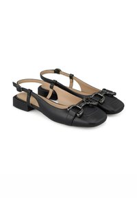 Zapatos de charol negros tipo slingback con punta cuadrada, tacón plano y detalles decorativos de hebilla. Por dentro tienen una plantilla de color nude.