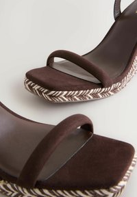 Sandali con tacco in suede marrone, con punta quadrata, dotati di due strap sottili e una piattaforma intrecciata simile a juta con un motivo a spina di pesce.