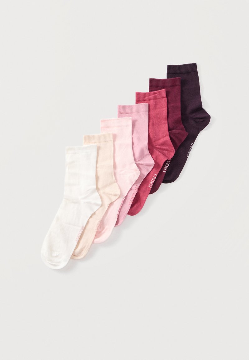 Sju par ankelstrømper i en gradient av farger fra hvit til mørk lilla, arrangert i en diagonal linje på en lys bakgrunn.