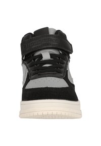 Korkeavartiset tennarit, joissa on mustaa nahkaa ja harmaata mokkaa. Ominaisuuksiin kuuluu tarranauha, mustat nauhat ja valkoinen kumipohja.