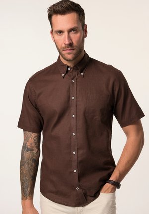 Camisa de manga corta en color marrón oscuro, de tela texturizada, con cuello tipo botón, botones blancos y un bolsillo en el pecho.
