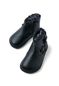 Botas de tobillo de cuero negro con cierre de cremallera, forro gris suave y acentos florales negros en el lado exterior. Textura suave, diseño de punta redondeada.