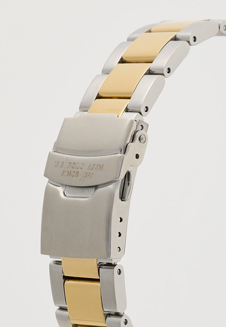 Orologio da polso in metallo con bracciale in argento e oro. Presenta una chiusura con testo inciso e maglie alternate lisce e spazzolate.