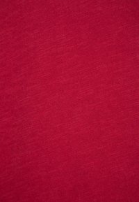 Texture de tissu rouge uni avec un léger motif de tissage et des variations subtiles de teintes.