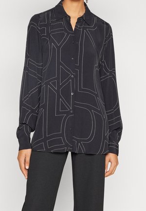 Dunkelbluse mit langen Ärmeln und Knöpfen. Verfügt über weiße geometrische Stickmuster. Hergestellt aus glattem Stoff mit einem strukturierten Kragen.