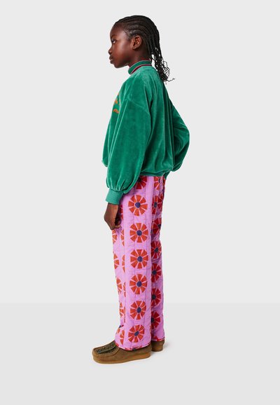 Sweatshirt en velours vert avec des manches ballon et un col côtelé, assorti à un pantalon rose à motifs avec des fleurs rouges et un centre bleu.