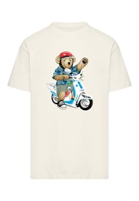 Camiseta crema con la imagen de un oso que lleva una camisa de patrón azul, pantalones cortos caquis y un casco rojo, montando un patinete blanco con detalles gráficos.