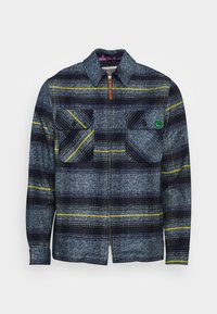 Herre flannel skjorte i blå og grå ternet mønster med gule striber. Har to brystlommer, knaplukning og krave. Holdbart stof tekstur.