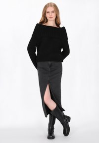 Fekete, vállnélküli kötött pulóver, amelyet egy magas derekú fekete farmer szoknyával párosítanak, elöl hasítékkal. Térd fölé érő fekete csizmával viselve.