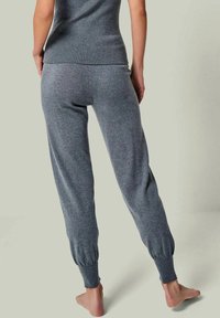 Grau gestrickte Jogginghosen mit elastischen Bündchen, die eine weiche Textur und eine lockere Passform aufweisen, von hinten gezeigt.