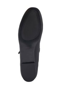 Parte inferior de un zapato negro con una suela de goma texturizada, que cuenta con ranuras para tracción y una sección lisa en el talón. Nombre de la marca "MNG" visible.