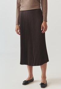 Jupe plissée marron foncé, composée d'un matériau lisse. Présente un design longueur genoux avec des plis verticaux et une silhouette fluide.