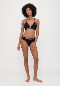 Czarny zestaw bikini z trójkątnym stanikiem i majtkami z niskim stanem. Paski z napisem "MOSCHINO" oraz "I ❤️ YOU" w czerwonym i białym kolorze. Miękka tkanina.
