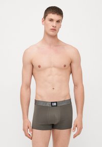Olíva zöld, elasztikus anyagú férfi boxer alsónadrág, szürke rugalmas derékszíjjal, logó részletekkel és szoros, testhezálló kialakítással.