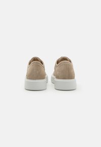 Beige semskinn sneakers med lav profil, hvit gummisåle, rund tå og minimal sømdetalj på hælen.