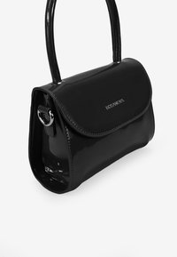 Sac à main en vernis noir avec un design structuré, des côtés courbés, un fermoir à rabat et une longue anse. Comprend un logo argenté et des accessoires en métal.