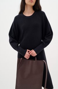 Navy oversized kötött ruha bordás nyakkivágással, sima, téglalap alakú barna bőrtáskával párosítva. Részletei között szerepel hosszú ujj és finom textúra.