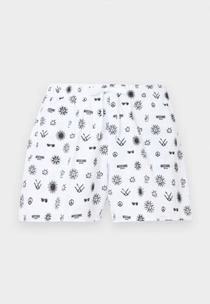 Shorts blancs avec motifs noirs de soleil, signe de la paix, lunettes de soleil, cafetière, bâtons croisés et texte "Moschino Swim".