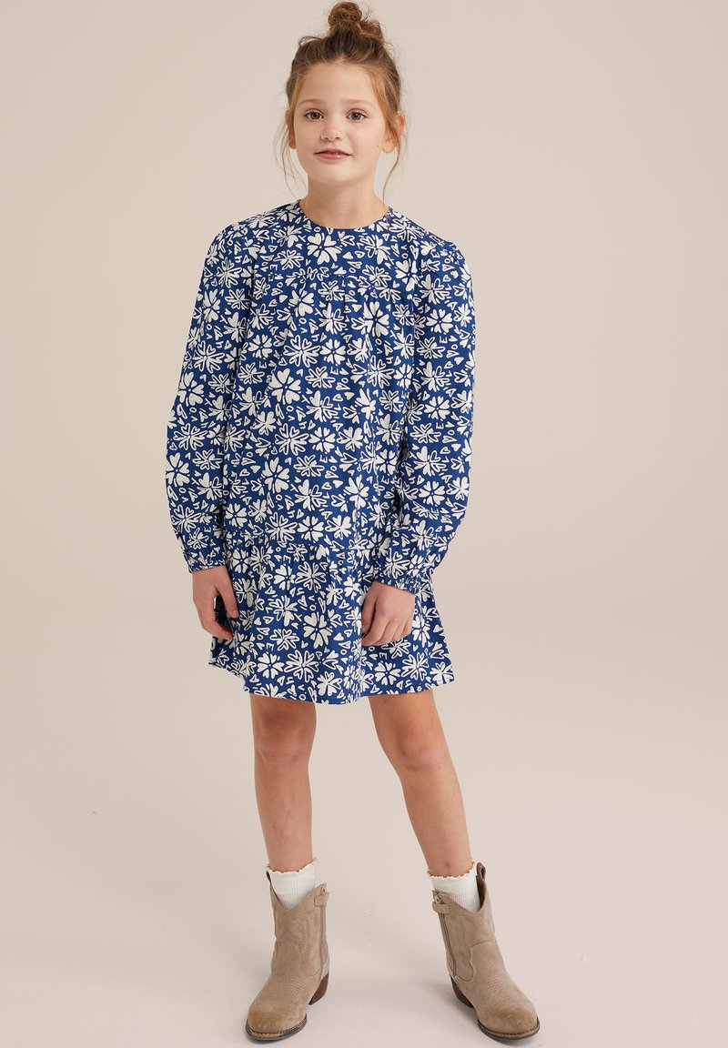 Zila ziedu kleita ar garām piedurknēm, balts ziedu raksts, plisēta detaļa jostasvietā, kombinēta ar bēšiem potīšu zābakiem un krēmkrāsas zeķēm.