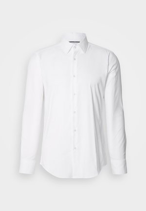 Valge pika varrukaga särk, mis on valmistatud siledast kangast. Sellel on klassikaline krae ja nööpidega esiosa, millel on kaarjas alläär. Nööpide pind on õrnalt läikiv.