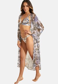 Lichtgewicht, doorschijnende strandcover-up met bloemmotief in aardetinten. Voorzien van lange mouwen en een open voorkant, gecombineerd met een gemusterd bikini-set.