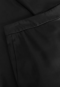 Black textile featuring a smooth, shiny finish with seams and folds; material appears lightweight and soft to the touch.